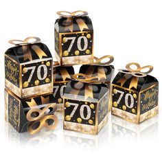 four black and gold boxes with 70th birthday decorations on them, all wrapped in ribbon