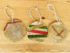 three handmade christmas ornaments hanging on a wooden table with string and beadwork