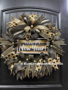 a black and gold new year's wreath hanging on a door with the words happy new year