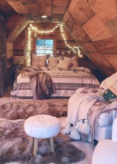 an attic bedroom is decorated in rustic wood and white fur, with lights strung from the ceiling