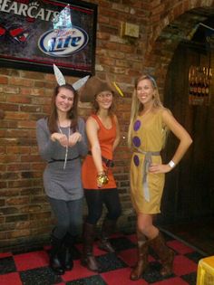 three women standing in front of a brick wall wearing bunny ears and holding their hands up