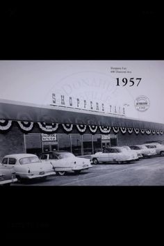 an old black and white photo of cars parked in front of a store