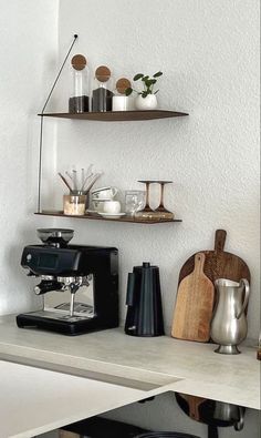 two shelves above a counter with coffee cups and other items on top of the shelf