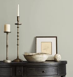 a table with a bowl and two candles on it, next to a framed photograph