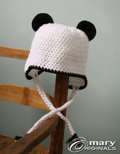 a crocheted panda bear hat on top of a wooden chair