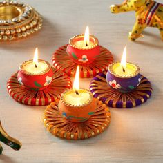 colorful candles are sitting on a table with an elephant figurine in the background