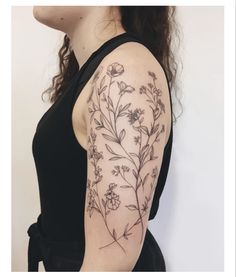 a woman's arm with flowers and leaves on the back of her left arm