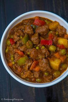 a white bowl filled with stew on top of a wooden table