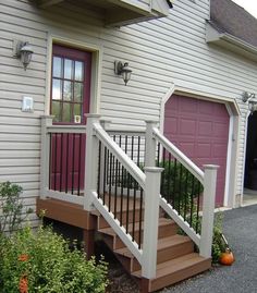 a house with stairs leading up to the front door and entry way, next to a flower bed