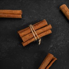 cinnamon sticks tied with twine on black surface