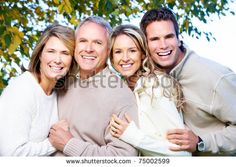 a group of people standing next to each other in front of a leafy tree