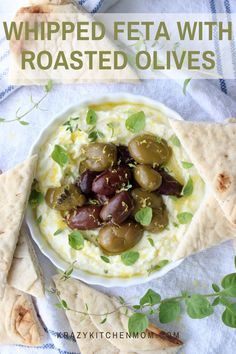 a bowl filled with hummus and olives next to pita bread