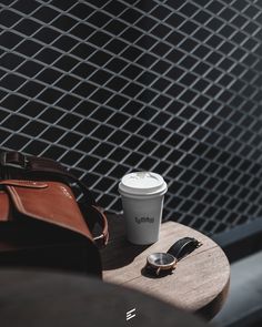 a coffee cup sitting on top of a table next to a cell phone and wallet