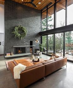 a living room with large windows and a couch in front of a fire place on the wall