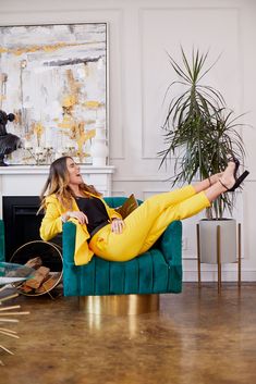 a woman in yellow pants is sitting on a green couch