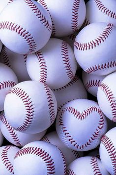 a pile of white baseballs with red stitching