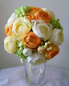 a vase filled with lots of flowers on top of a white cloth covered tablecloth