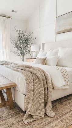 a bedroom with a large bed and a bench in the corner next to it on an area rug