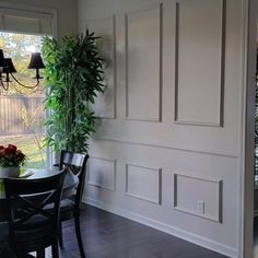 a dining room table and chairs in front of a window with potted plants on it