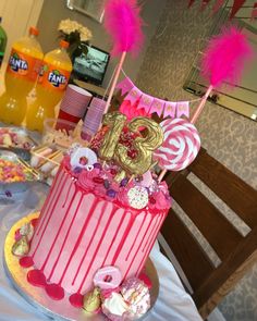 a pink and gold birthday cake sitting on top of a table next to other desserts