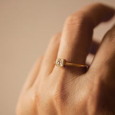 a person's hand with a gold ring on their left and a diamond in the middle