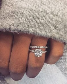 a woman's hand with two engagement rings on it and a diamond ring in the middle