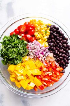 a bowl filled with black beans, tomatoes, and other veggies on top of a white table