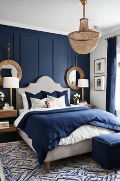 a bedroom with blue walls, white bedding and two lamps hanging from the ceiling