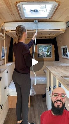 a man and woman are standing in the back of a tiny house with an overhead window