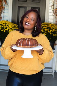 a woman holding a bundt cake on a plate