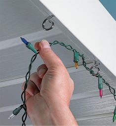 a hand is holding some wires and plugs in the ceiling with other cords attached to it