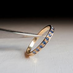 a gold ring with blue sapphires is being held up by a pair of scissors