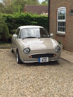 an old car parked in front of a brick building with a white license plate on it