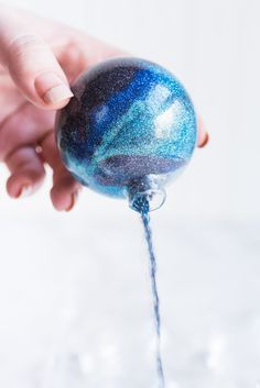 a person is holding a blue and black ball with water running from it to the ground