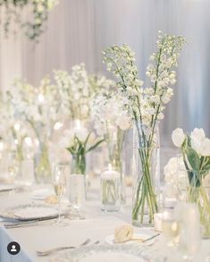 there are many vases with flowers on the table at this wedding reception, one is filled with baby's breath