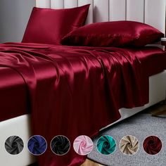 the bed is covered with red sheets and pillows, along with several different color options