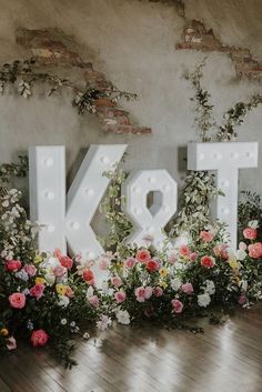 the letters k and t are lit up with flowers in front of them on display