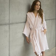 a woman in a bathrobe leaning against a wall