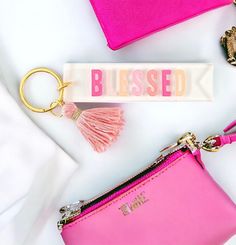 a pink purse and keychain with the word blessing on it next to other items