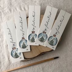 six christmas ornaments with handwritten names on them and a pencil sitting next to them