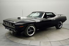 a black muscle car is on display in a showroom with no people around it