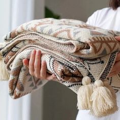 a woman holding a blanket with tassels on it