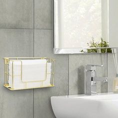 a white sink sitting next to a mirror and a metal rack with towels on it