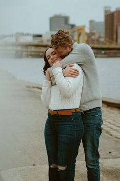 a man and woman standing next to each other near the water