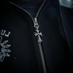 a close up of a person wearing a black jacket with a silver cross on it