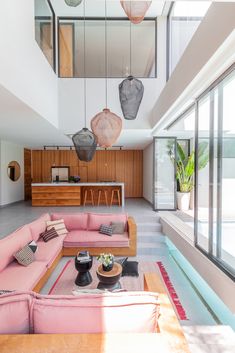 a living room filled with pink couches next to a kitchen and dining room table