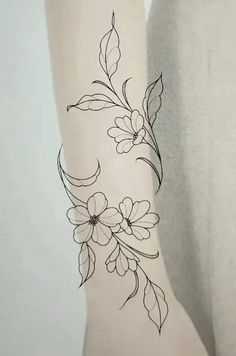 a woman's arm with flowers and leaves tattooed on the back of her leg