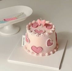 a pink cake sitting on top of a white table next to a plate with a toothbrush