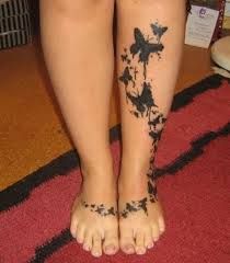 a woman's legs with black butterflies on them and her leg is covered in tattoos