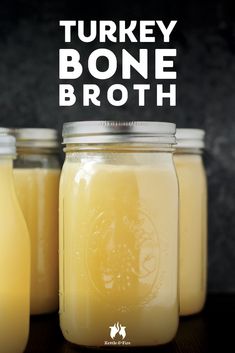 three jars filled with yellow liquid sitting on top of a wooden table next to each other